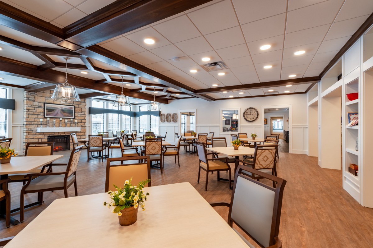 A spacious and modern dining room with neatly arranged tables and chairs, featuring elegant lighting and decor.
