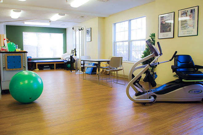 A well-equipped fitness room with exercise machines and a large exercise ball.