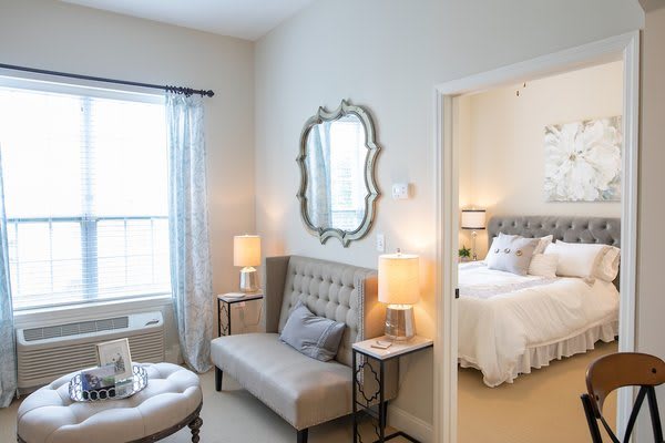 A cozy and elegantly decorated bedroom with a comfortable seating area, featuring soft lighting and stylish furnishings.