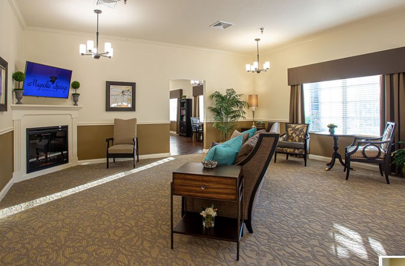 A well-lit living room with elegant furnishings, chandeliers, and large windows.
