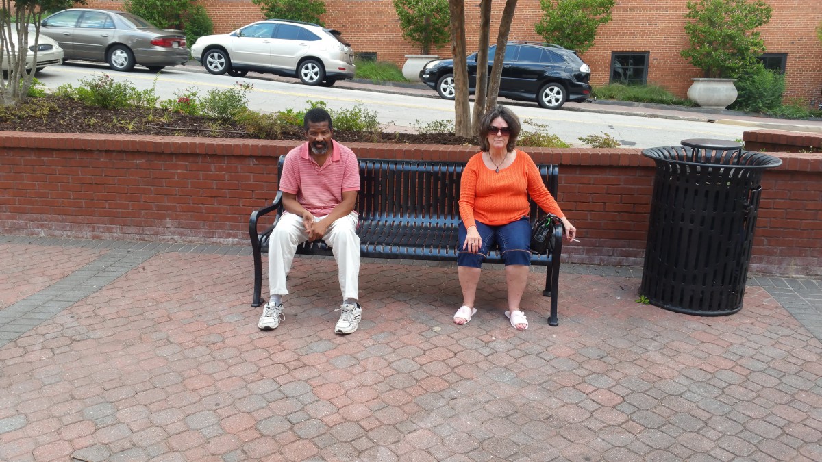 Two people sitting on a bench in an urban area.