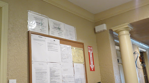 An office wall displaying certificates and various documents on a bulletin board.