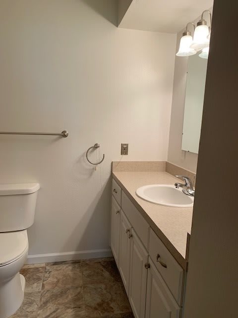 A simple bathroom with a sink, vanity, and toilet.
