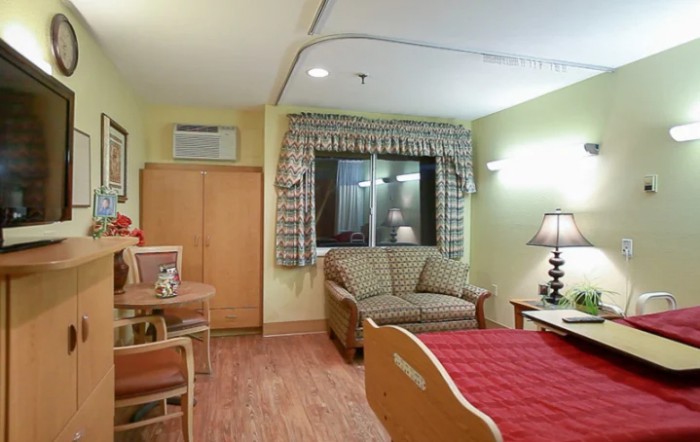 A well-furnished hospital room with a bed, sofa, and table.