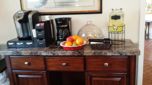 A cozy kitchen corner featuring a variety of fresh fruits on display, a coffee maker, and a beverage dispenser.