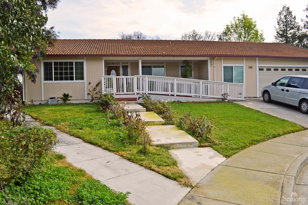 A suburban house with a ramp leading to the front entrance, surrounded by a well-maintained lawn.