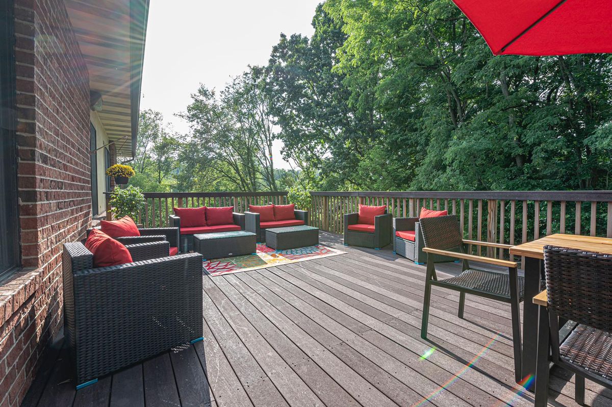 A spacious outdoor deck with comfortable seating and red cushioned furniture, surrounded by greenery.