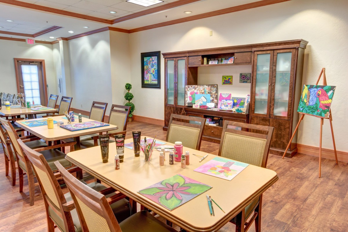 An art room with tables set up for creative activities, featuring paintings and art supplies.