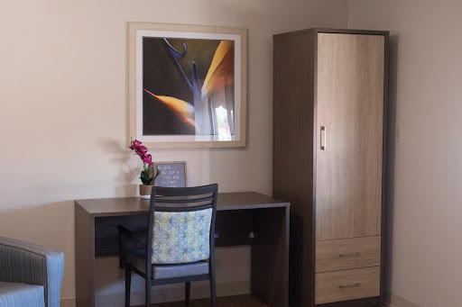 A simple and organized office space featuring a desk, chair, storage cabinet, and artwork.