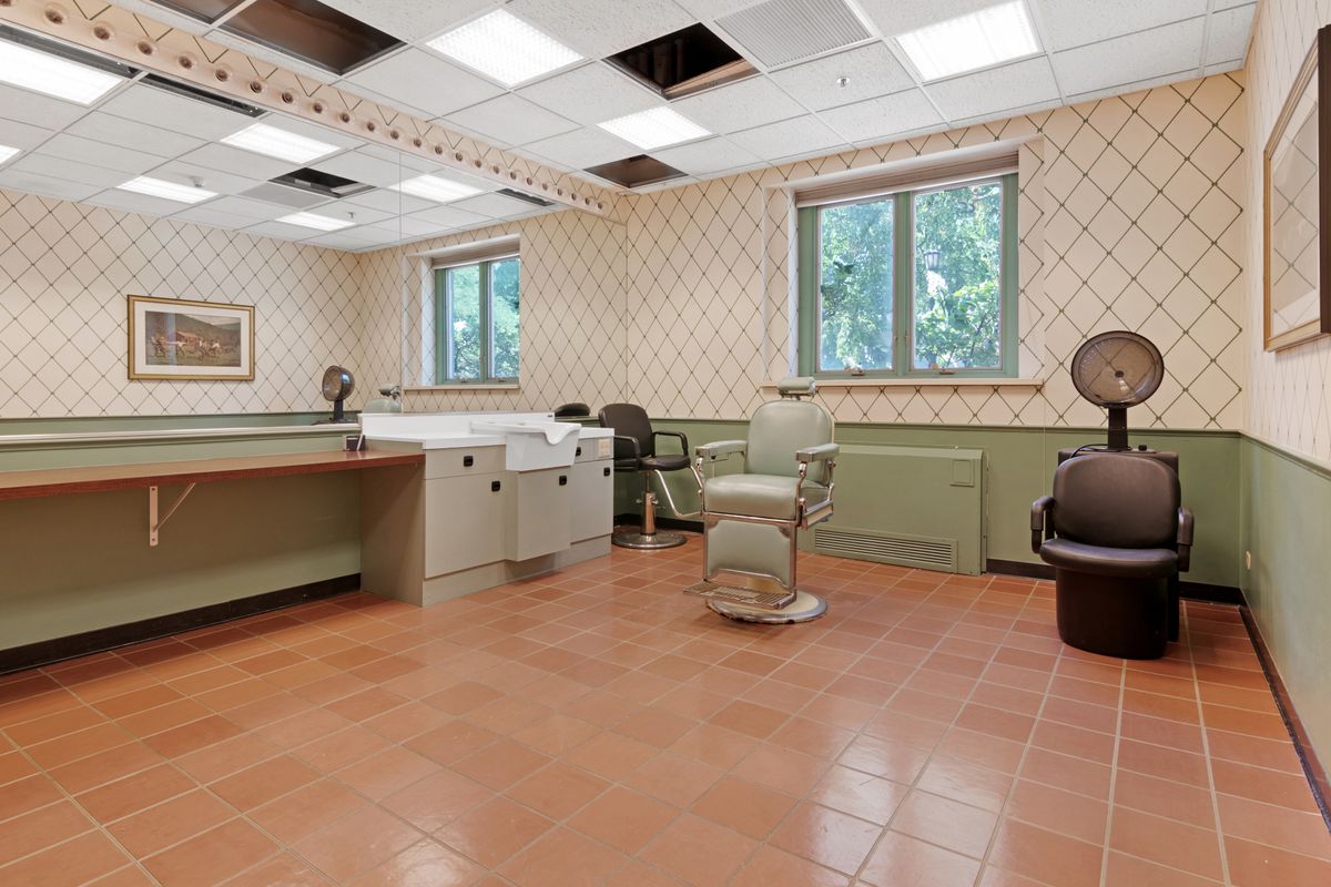 A spacious salon interior with a barber chair, mirrors, and hair dryers.