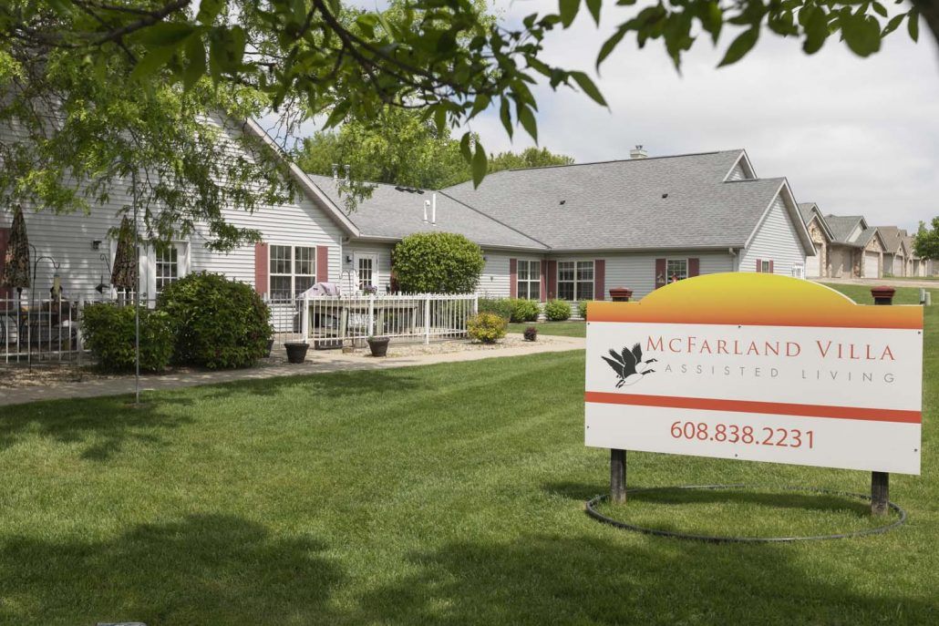 A residential building with a well-maintained lawn and a sign in the foreground.