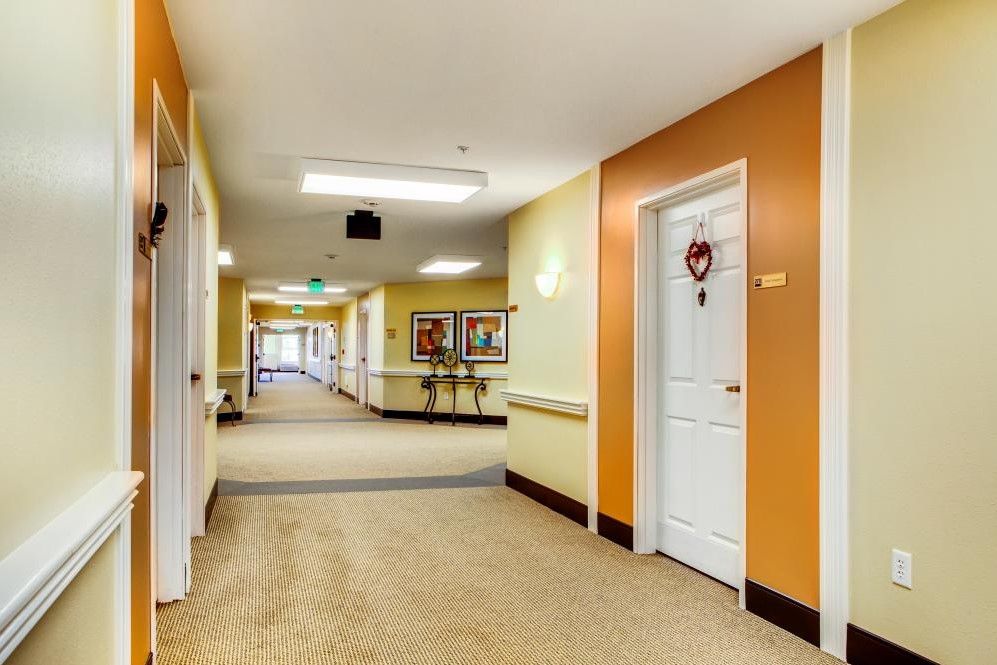 A brightly lit hallway with several doors and framed artwork on the walls.