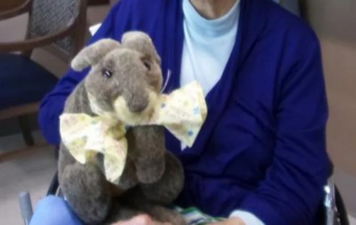A person holding a plush rabbit toy with a bow tie.