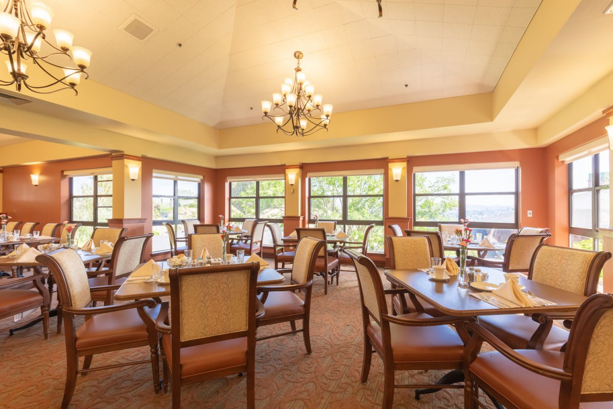 A well-lit dining area with elegant furniture and a central chandelier.