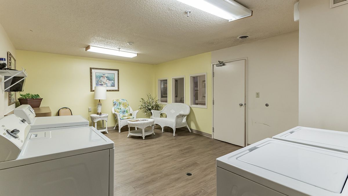 A cozy laundry room featuring a sitting area with wicker furniture and washing machines.