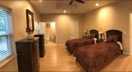 A cozy bedroom featuring twin beds with plaid bedding, complemented by warm lighting and a bathroom entrance.