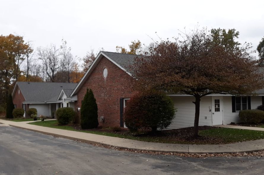 A suburban residential building with brick exterior and a tree-lined sidewalk.