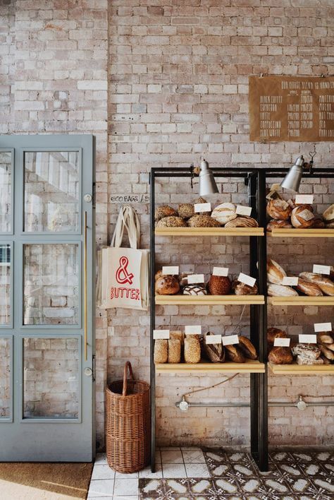 A cozy bakery interior with shelves displaying a variety of bread loaves against a rustic brick wall.