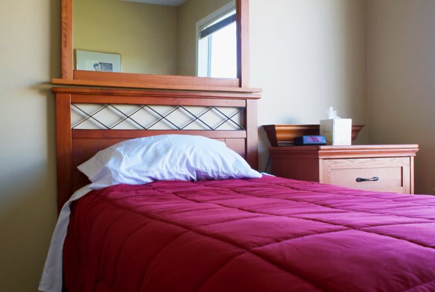 A cozy bedroom setup with a red blanket and wooden furniture.