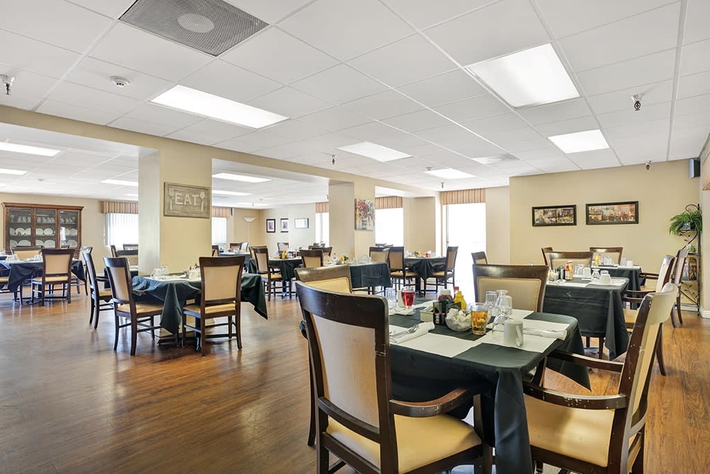 An empty dining room with neatly arranged tables and chairs, set for a meal.