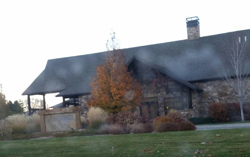 A charming stone house with a sloped roof and autumn foliage in the garden.