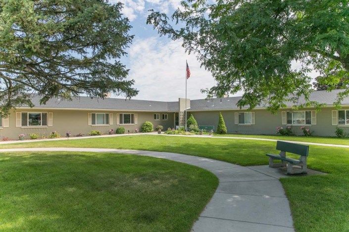 A single-story building with a well-maintained lawn and a flagpole in front.