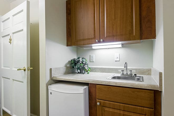 A small kitchenette with wooden cabinets, a sink, and a mini fridge.