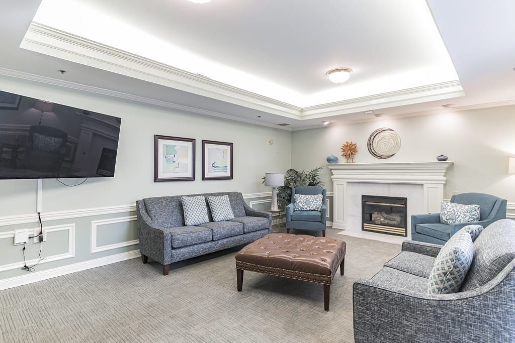 A well-furnished living room featuring a comfortable sofa set, a central coffee table, and a fireplace with elegant wall art.