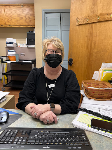 A receptionist wearing a mask at her desk in an office environment.