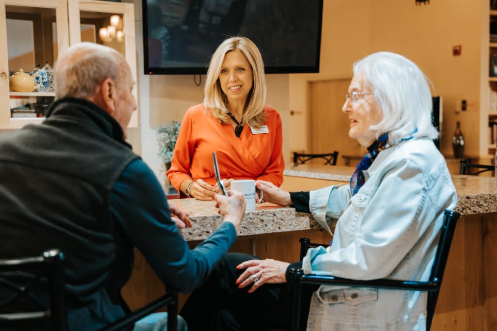 A caregiver interacting with elderly individuals at a care facility.