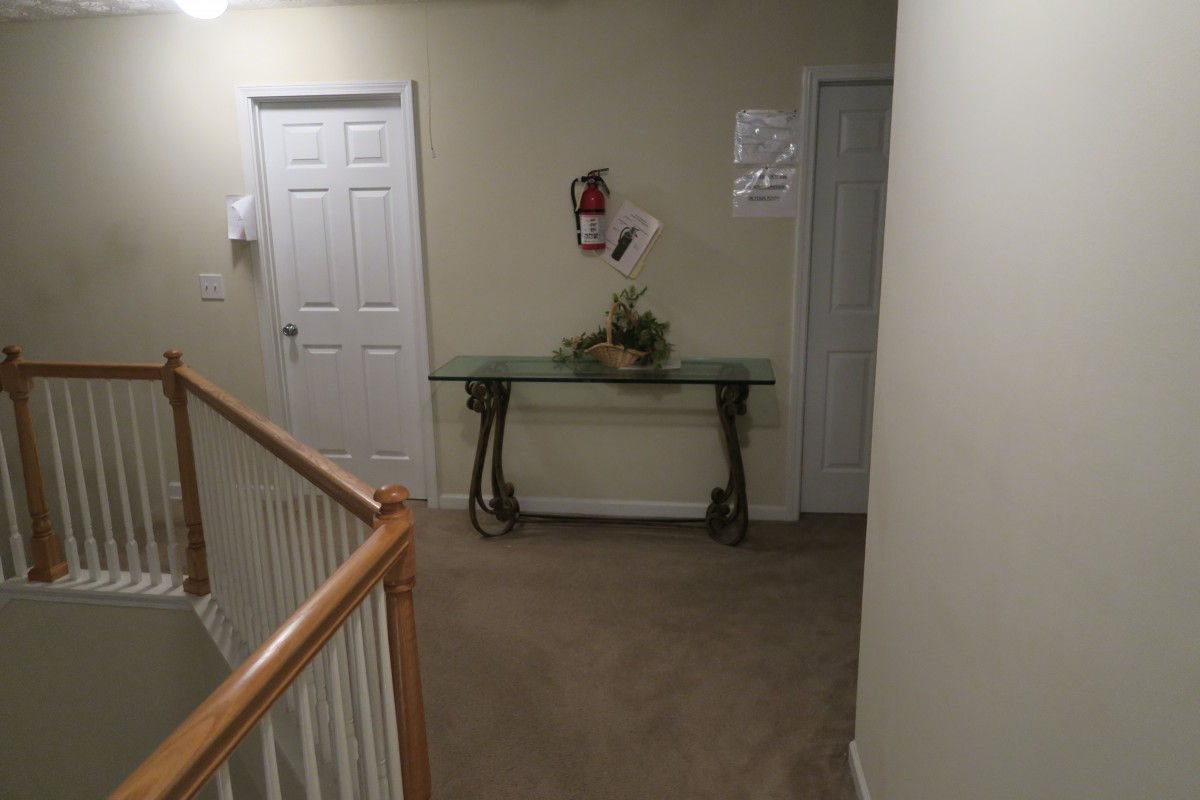 A hallway with a glass table, two doors, and a fire extinguisher on the wall.