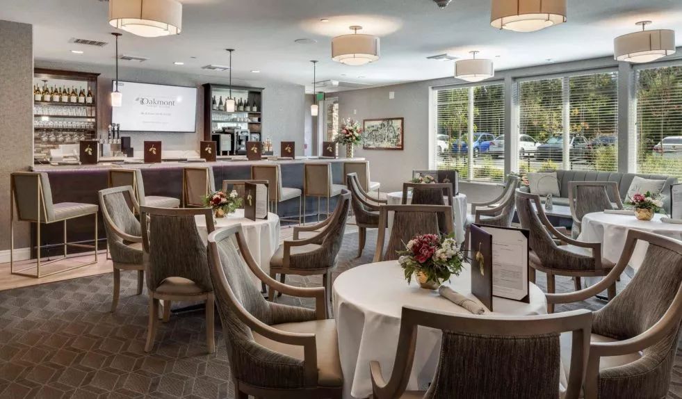 A modern restaurant interior with elegantly set tables and a bar area.