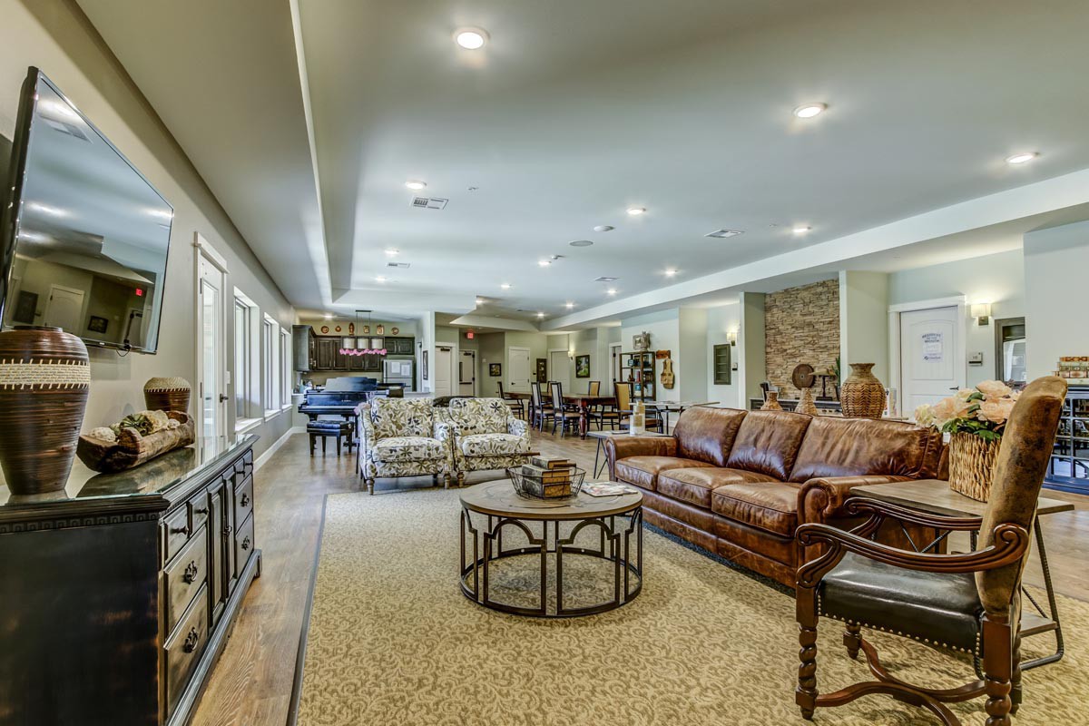 A spacious and well-decorated living room with comfortable seating, tables, and ample lighting.