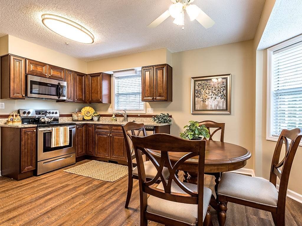A cozy kitchen with wooden cabinets, modern appliances, and a dining area featuring a round table and chairs.