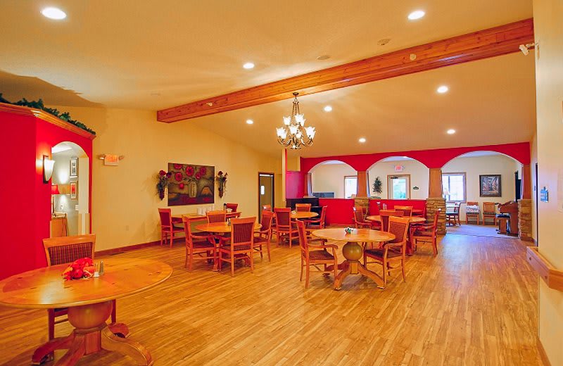A spacious restaurant dining area with wooden floors, tables, and a chandelier.