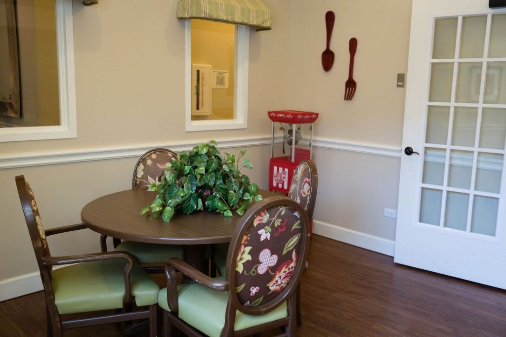 A cozy dining area with a round table, floral-patterned chairs, and a small popcorn machine in the corner.