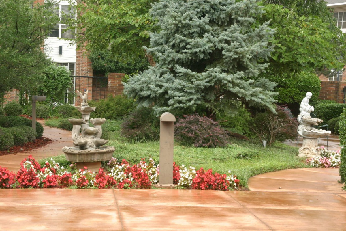 A serene garden scene with a fountain, colorful flowers, and lush greenery.