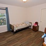 A minimalist bedroom with a single bed and wooden flooring.
