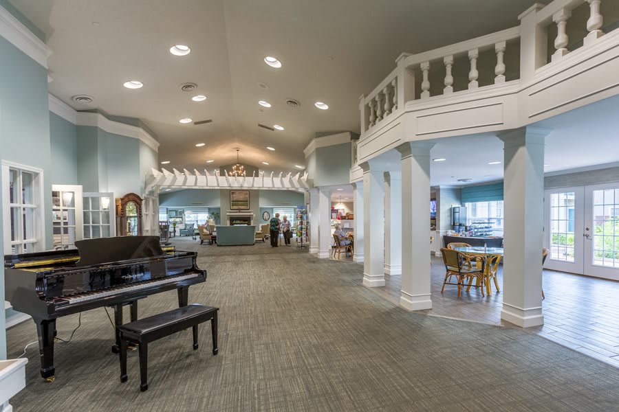 Elegant lobby with a grand piano and chandelier, featuring classical architecture.