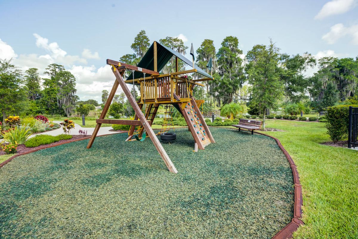 A wooden playground set surrounded by greenery in a park.