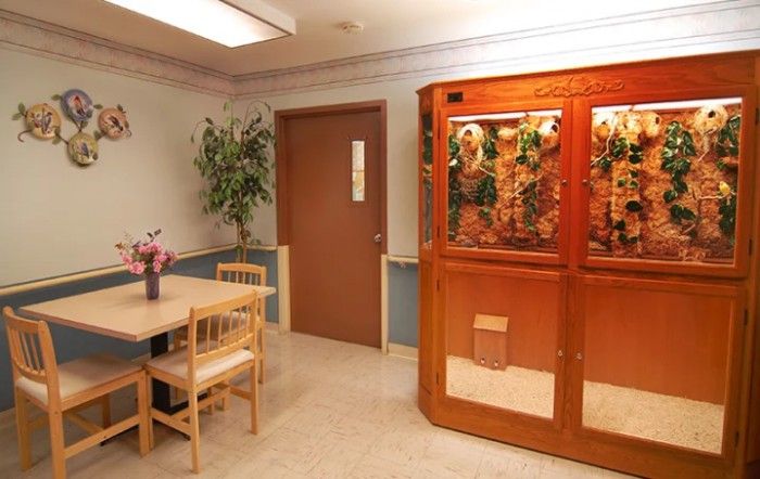 A waiting room with a table, chairs, and an aquarium.
