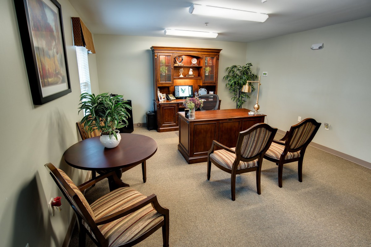 A neatly arranged office with wooden furniture and indoor plants.