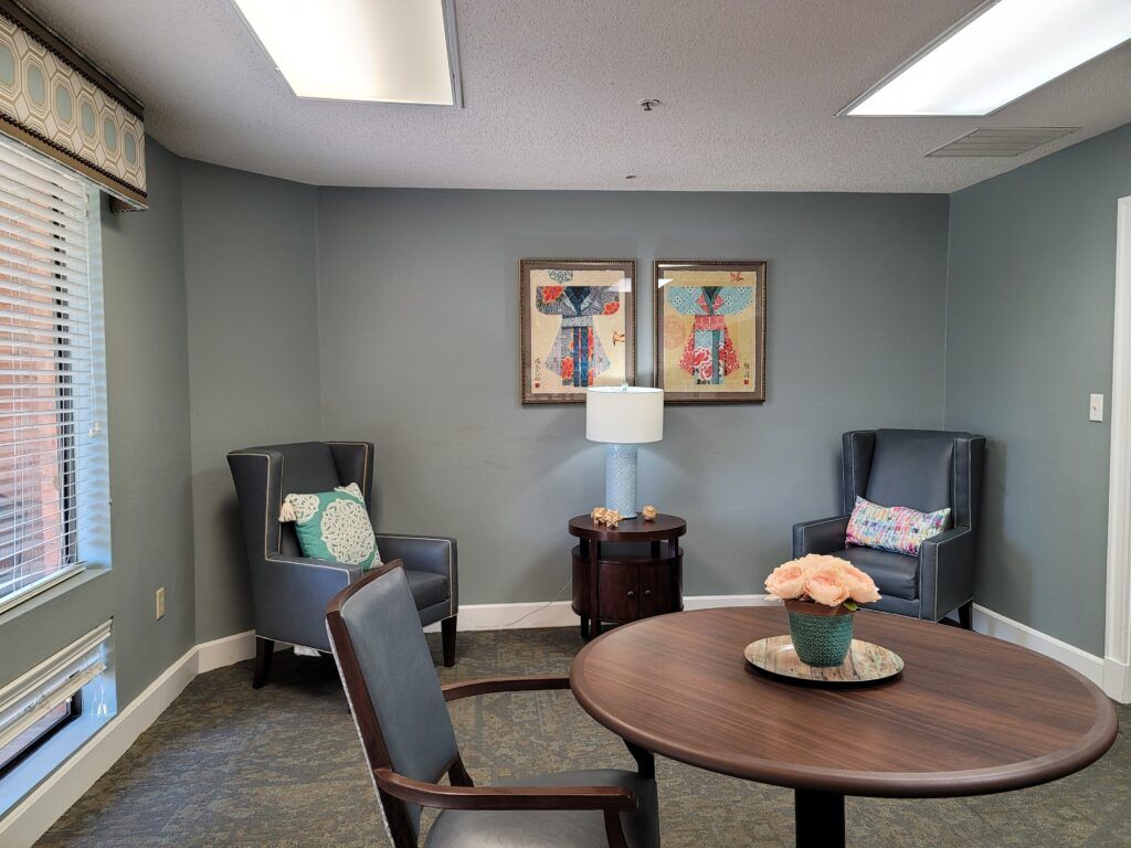A cozy meeting room with chairs, a round table, and decorative artwork.