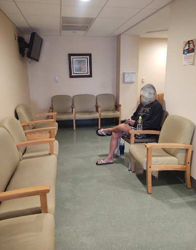 A quiet waiting room with a single patient seated.