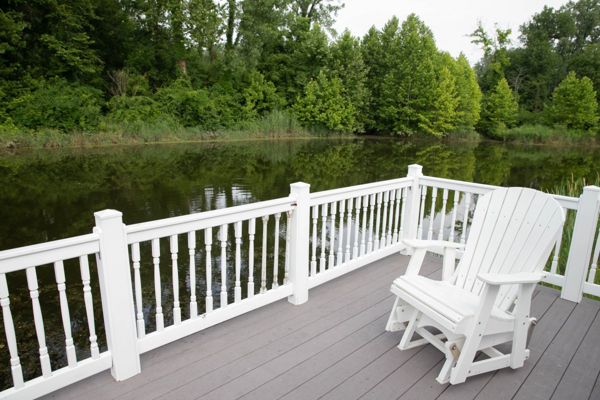 A serene deck overlooking a tranquil lake with surrounding trees.