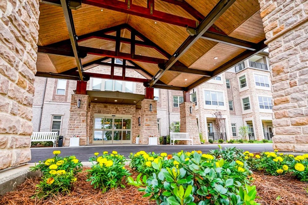 A building entrance with colorful flowers and well-maintained landscaping.