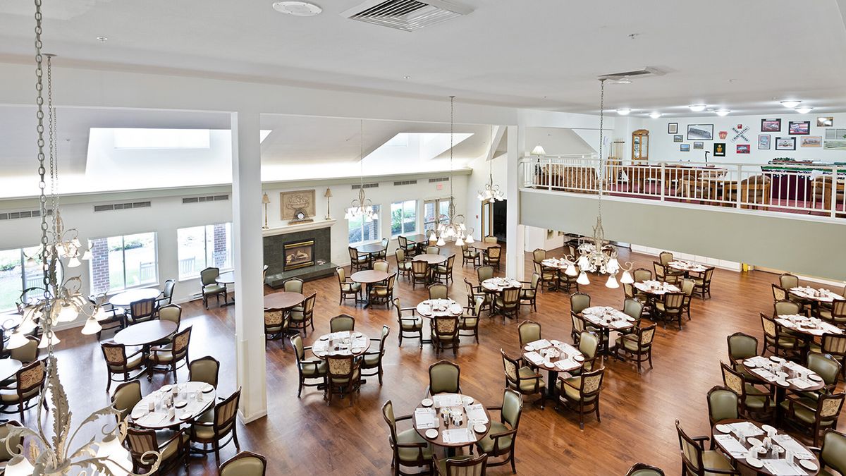 A spacious dining area with neatly arranged tables and chairs, featuring elegant decor and wooden flooring.
