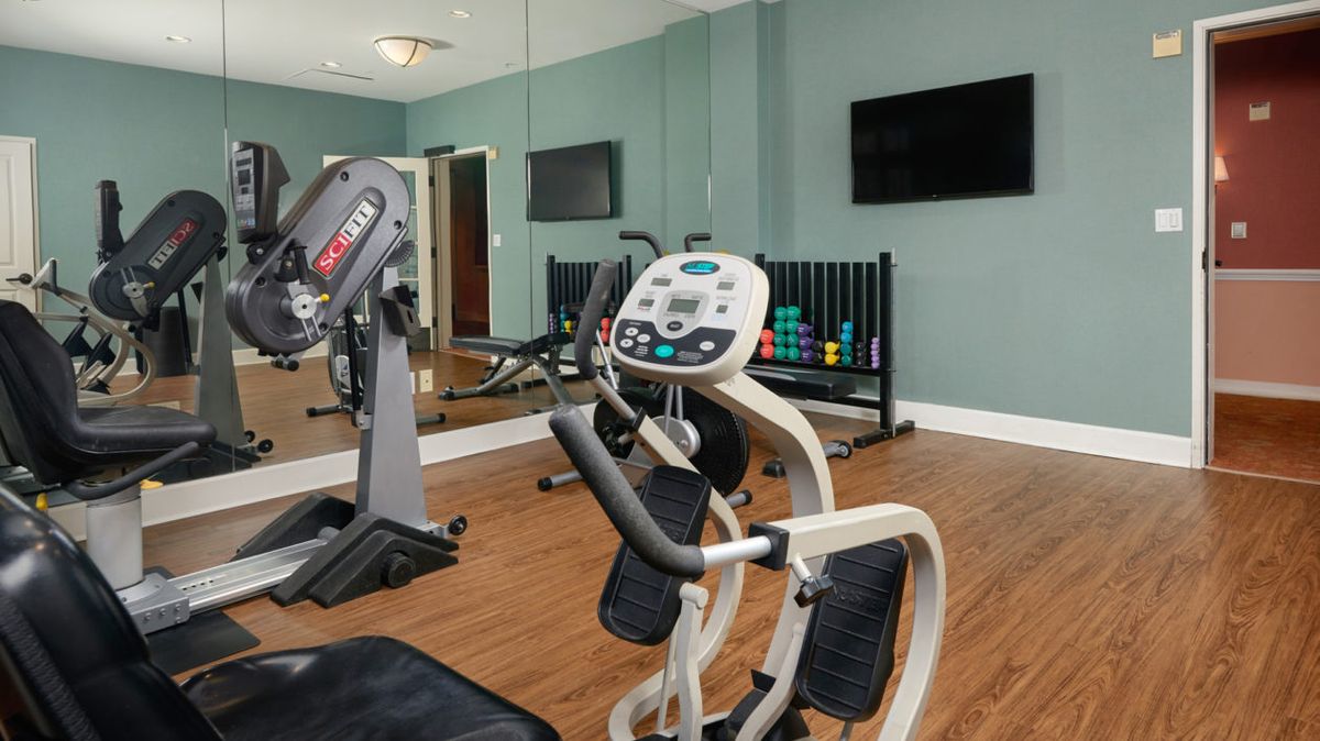 A modern gym featuring various exercise equipment including an elliptical and weights.