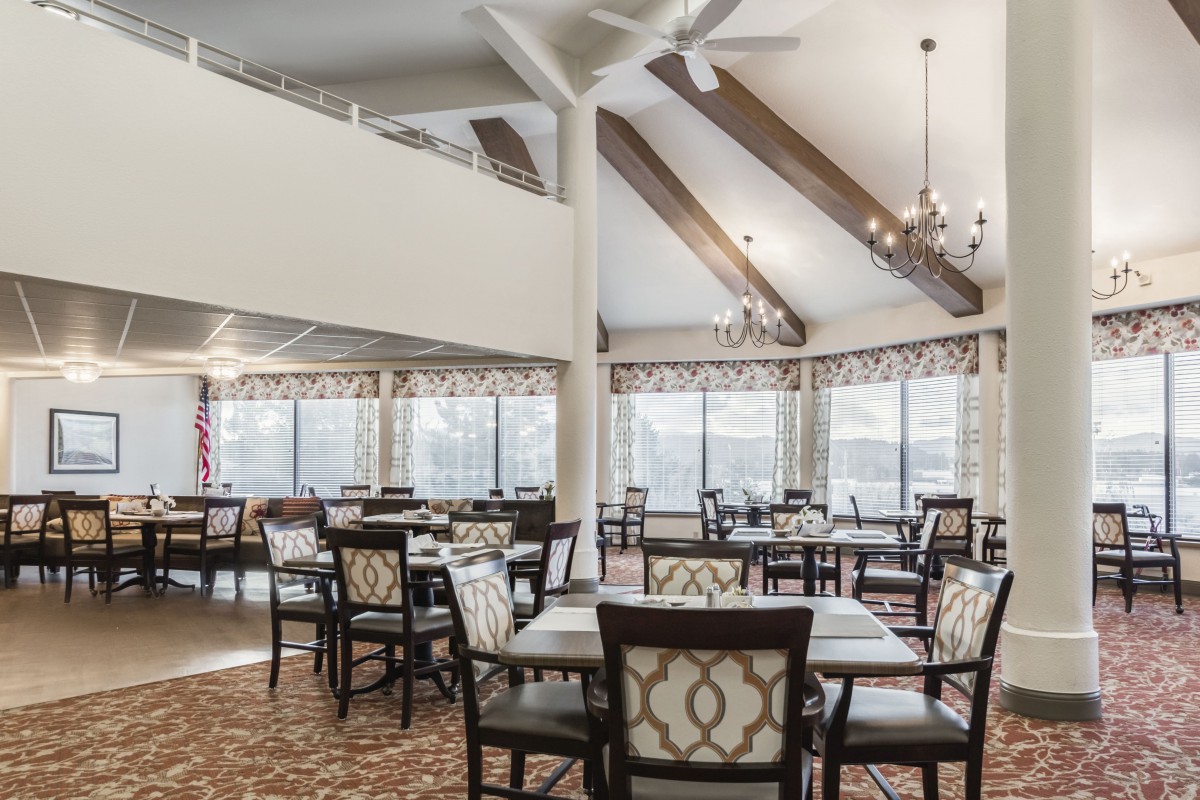 A spacious dining area with elegant chandeliers and large windows providing natural light.