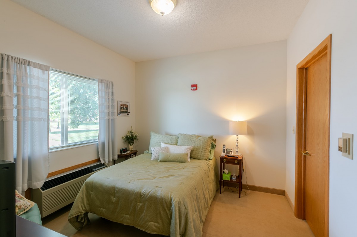 A cozy and minimalist bedroom interior with a bed, lamp, and window.